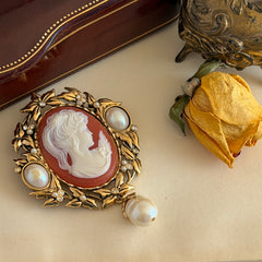 Vintage KJL for Avon gold tone cameo brooch pendant with resin cameo, faux pearls, clear rhinestones, and ornate detailing.