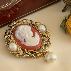 Vintage KJL for Avon gold tone cameo brooch pendant with resin cameo, faux pearls, clear rhinestones, and ornate detailing.