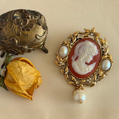 Vintage KJL for Avon gold tone cameo brooch pendant with resin cameo, faux pearls, clear rhinestones, and ornate detailing.