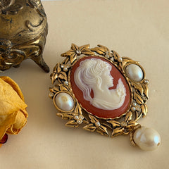 Vintage KJL for Avon gold tone cameo brooch pendant with resin cameo, faux pearls, clear rhinestones, and ornate detailing.