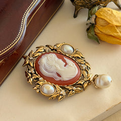 Vintage KJL for Avon gold tone cameo brooch pendant with resin cameo, faux pearls, clear rhinestones, and ornate detailing.