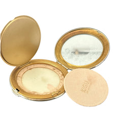 Vintage 1950s Kigu gold-tone powder compact with guilloché moiré lid, original puff, and mirror—collectible beauty accessory with timeless charm.
