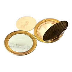 Vintage 1950s Kigu gold-tone powder compact with guilloché moiré lid, original puff, and mirror—collectible beauty accessory with timeless charm.

