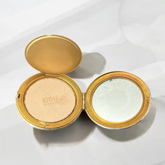 Vintage 1950s Kigu gold-tone powder compact with guilloché moiré lid, original puff, and mirror—collectible beauty accessory with timeless charm.
