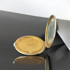 Vintage 1950s Kigu gold-tone powder compact with guilloché moiré lid, original puff, and mirror—collectible beauty accessory with timeless charm.
