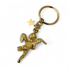Gold-tone vintage Kirk’s Folly keychain featuring a winged cherub holding a small object, with a dangling star charm; detailed and symbolic design from the late 1980s–early 1990s.