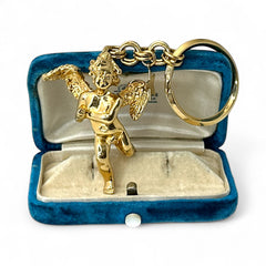 Gold-tone vintage Kirk’s Folly keychain featuring a winged cherub holding a small object, with a dangling star charm; detailed and symbolic design from the late 1980s–early 1990s.