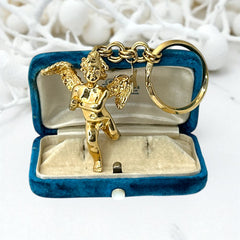 Gold-tone vintage Kirk’s Folly keychain featuring a winged cherub holding a small object, with a dangling star charm; detailed and symbolic design from the late 1980s–early 1990s.