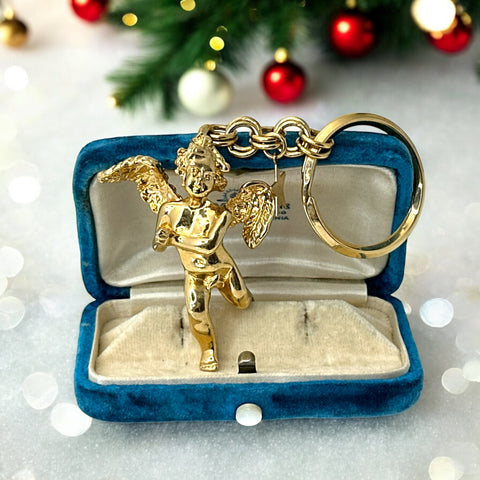 Gold-tone vintage Kirk’s Folly keychain featuring a winged cherub holding a small object, with a dangling star charm; detailed and symbolic design from the late 1980s–early 1990s.