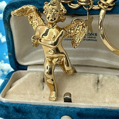 Gold-tone vintage Kirk’s Folly keychain featuring a winged cherub holding a small object, with a dangling star charm; detailed and symbolic design from the late 1980s–early 1990s.