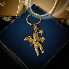 Gold-tone vintage Kirk’s Folly keychain featuring a winged cherub holding a small object, with a dangling star charm; detailed and symbolic design from the late 1980s–early 1990s.