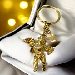 Gold-tone vintage Kirk’s Folly keychain featuring a winged cherub holding a small object, with a dangling star charm; detailed and symbolic design from the late 1980s–early 1990s.