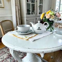 White porcelain teapot‑and‑cup set from La Route des Comptoirs with the boat‑and‑tea‑leaf logo on each piece