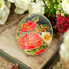 Hand-painted floral brooch and screw-back earrings set in lacquered wood with gold-tone trim, featuring red and pink flowers on a black background, signed by the artist.