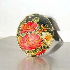 Hand-painted floral brooch and screw-back earrings set in lacquered wood with gold-tone trim, featuring red and pink flowers on a black background, signed by the artist.