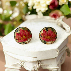 Hand-painted floral brooch and screw-back earrings set in lacquered wood with gold-tone trim, featuring red and pink flowers on a black background, signed by the artist.