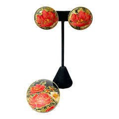 Hand-painted floral brooch and screw-back earrings set in lacquered wood with gold-tone trim, featuring red and pink flowers on a black background, signed by the artist.