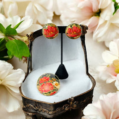 Hand-painted floral brooch and screw-back earrings set in lacquered wood with gold-tone trim, featuring red and pink flowers on a black background, signed by the artist.