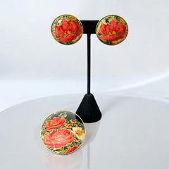 Hand-painted floral brooch and screw-back earrings set in lacquered wood with gold-tone trim, featuring red and pink flowers on a black background, signed by the artist.