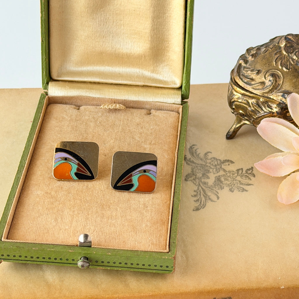 Vintage Laurel Burch “Tori Mon Bird of the Nile” square post earrings with orange, black, purple and green enamel bird motif on gold‑tone metal.