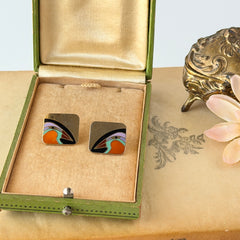 Vintage Laurel Burch “Tori Mon Bird of the Nile” square post earrings with orange, black, purple and green enamel bird motif on gold‑tone metal.