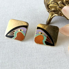 Vintage Laurel Burch “Tori Mon Bird of the Nile” square post earrings with orange, black, purple and green enamel bird motif on gold‑tone metal.