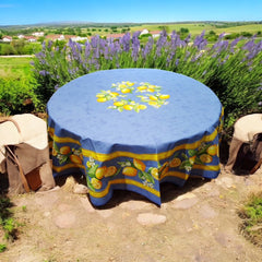 Provence coated cotton round tablecloth in blue with yellow lemon motif, green leaves, and lemon blossoms by Tissus Toselli.
