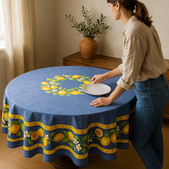 Provence coated cotton round tablecloth in blue with yellow lemon motif, green leaves, and lemon blossoms by Tissus Toselli.