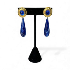 Vintage pierced earrings featuring glossy faux lapis long teardrop pendants and round blue cabochons set in gold-tone metal; likely acrylic components with cosmic speckled finish, measuring approx. 2¼" long, in very good vintage condition with minor glue visible on one cabochon edge.