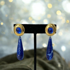 Vintage pierced earrings featuring glossy faux lapis long teardrop pendants and round blue cabochons set in gold-tone metal; likely acrylic components with cosmic speckled finish, measuring approx. 2¼" long, in very good vintage condition with minor glue visible on one cabochon edge.