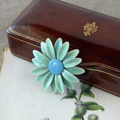 Vintage pastel green and blue enamel daisy brooch with layered petals and gold‑tone pin back, circa 1960s.