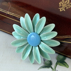 Vintage pastel green and blue enamel daisy brooch with layered petals and gold‑tone pin back, circa 1960s.