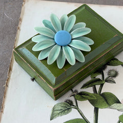 Vintage pastel green and blue enamel daisy brooch with layered petals and gold‑tone pin back, circa 1960s.