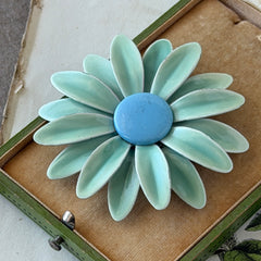 Vintage pastel green and blue enamel daisy brooch with layered petals and gold‑tone pin back, circa 1960s.