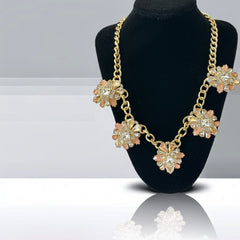 Gold tone statement necklace with five floral pendants featuring peach, champagne, and clear crystals in marquise, square, pear, and chaton cuts; adjustable curb chain with lobster clasp.