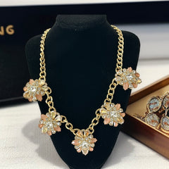 Gold tone statement necklace with five floral pendants featuring peach, champagne, and clear crystals in marquise, square, pear, and chaton cuts; adjustable curb chain with lobster clasp.