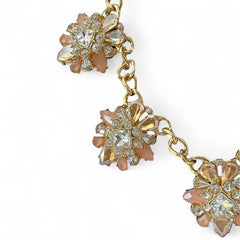 Gold tone statement necklace with five floral pendants featuring peach, champagne, and clear crystals in marquise, square, pear, and chaton cuts; adjustable curb chain with lobster clasp.