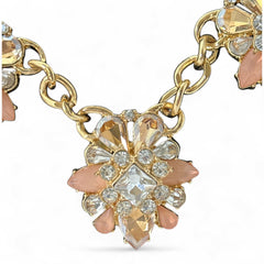 Gold tone statement necklace with five floral pendants featuring peach, champagne, and clear crystals in marquise, square, pear, and chaton cuts; adjustable curb chain with lobster clasp.