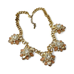 Gold tone statement necklace with five floral pendants featuring peach, champagne, and clear crystals in marquise, square, pear, and chaton cuts; adjustable curb chain with lobster clasp.