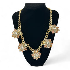 Gold tone statement necklace with five floral pendants featuring peach, champagne, and clear crystals in marquise, square, pear, and chaton cuts; adjustable curb chain with lobster clasp.