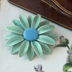 Vintage pastel green and blue enamel daisy brooch with layered petals and gold‑tone pin back, circa 1960s.