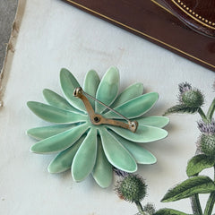Vintage pastel green and blue enamel daisy brooch with layered petals and gold‑tone pin back, circa 1960s.