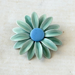 Vintage pastel green and blue enamel daisy brooch with layered petals and gold‑tone pin back, circa 1960s.