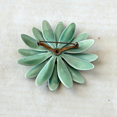 Vintage pastel green and blue enamel daisy brooch with layered petals and gold‑tone pin back, circa 1960s.