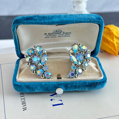 Vintage Lisner silver tone clip-on earrings with blue Aurora Borealis rhinestones in a leaf-shaped climber design, shown in various arrangements.