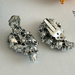 Vintage Lisner silver tone clip-on earrings with blue Aurora Borealis rhinestones in a leaf-shaped climber design, shown in various arrangements.