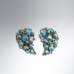 Vintage Lisner silver tone clip-on earrings with blue Aurora Borealis rhinestones in a leaf-shaped climber design, shown in various arrangements.