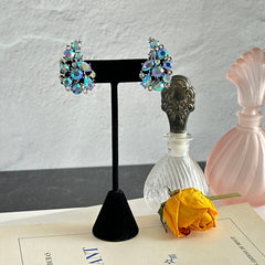 Vintage Lisner silver tone clip-on earrings with blue Aurora Borealis rhinestones in a leaf-shaped climber design, shown in various arrangements.
