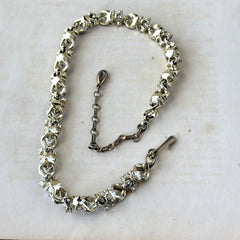 Vintage Lisner aurora‑borealis topaz and black enamel gold‑tone floral necklace with adjustable hook clasp and hangtag, shown on botanical background to highlight sparkle and craftsmanship.