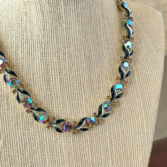 Vintage Lisner aurora‑borealis topaz and black enamel gold‑tone floral necklace with adjustable hook clasp and hangtag, shown on botanical background to highlight sparkle and craftsmanship.